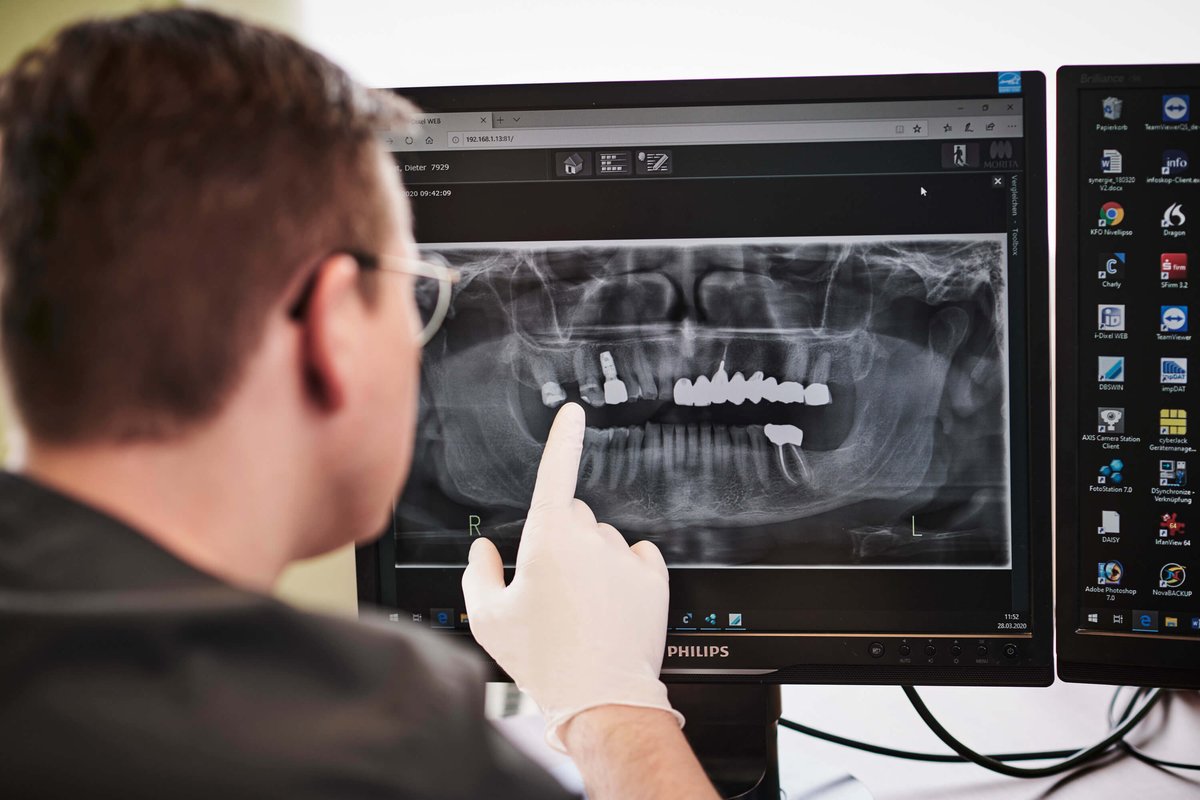 Behandelnder Zahnarzt erläutert Röntgenbild in der Zahnarztpraxis 32 schönezähne in Forchheim